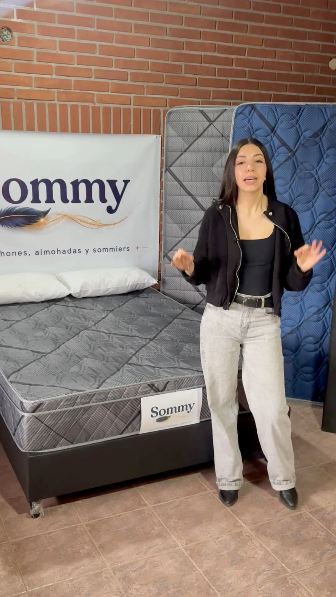 Ailén de pie frente a los colchones de Sommy, con el cartel de la marca atrás